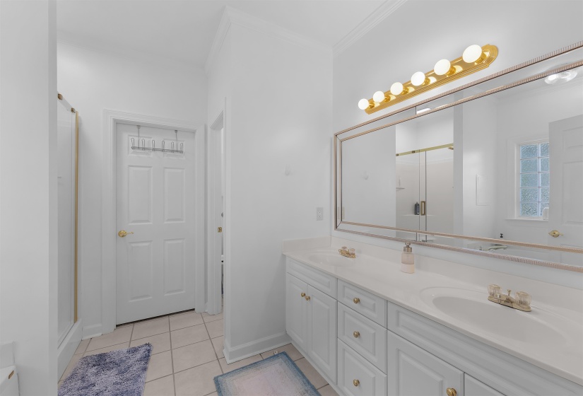 Double vanity featuring white cabinetry with gold-tone hardware, a light-toned countertop, and dual integrated sinks