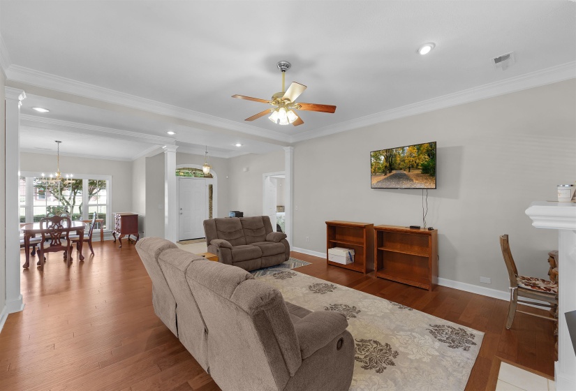 Spacious living area featuring wood-finish flooring, recessed lighting, and crown molding