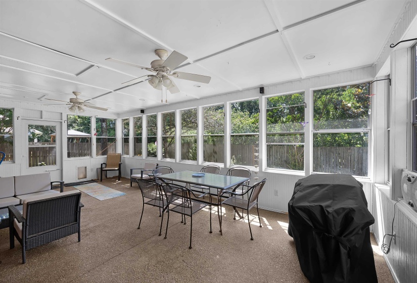 Spacious screened porch featuring a white tongue-and-groove ceiling, multiple ceiling fans, and abundant windows overlooking a fenced perimeter