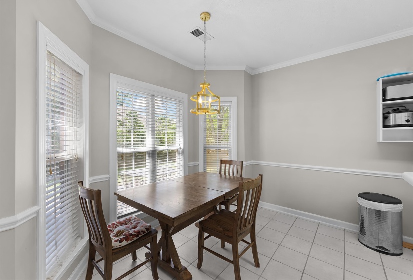 Dining area featuring a central chandelier, multiple windows with blinds, chair rail molding, and tile flooring
