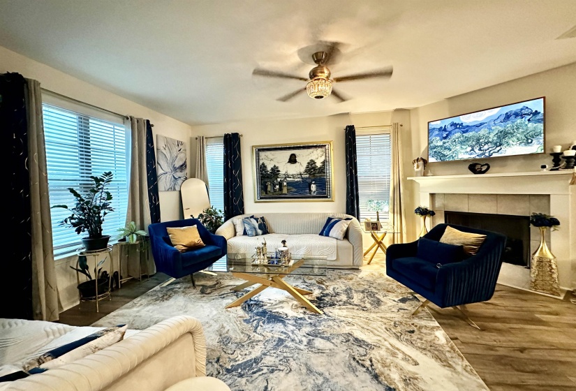 Spacious living area featuring wood-finish flooring, a white mantel, and a ventless fireplace with gas logs