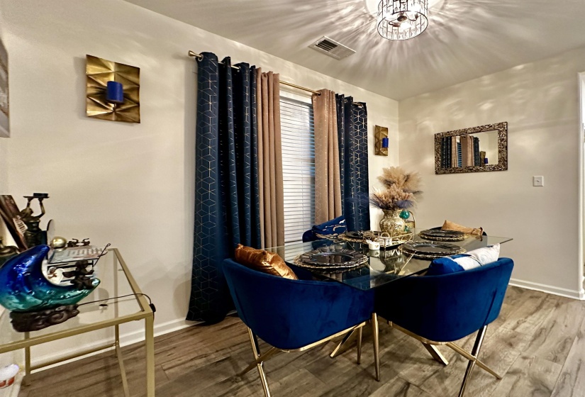 Dining area featuring wood-finish flooring, a contemporary ceiling light fixture, and a window with blinds