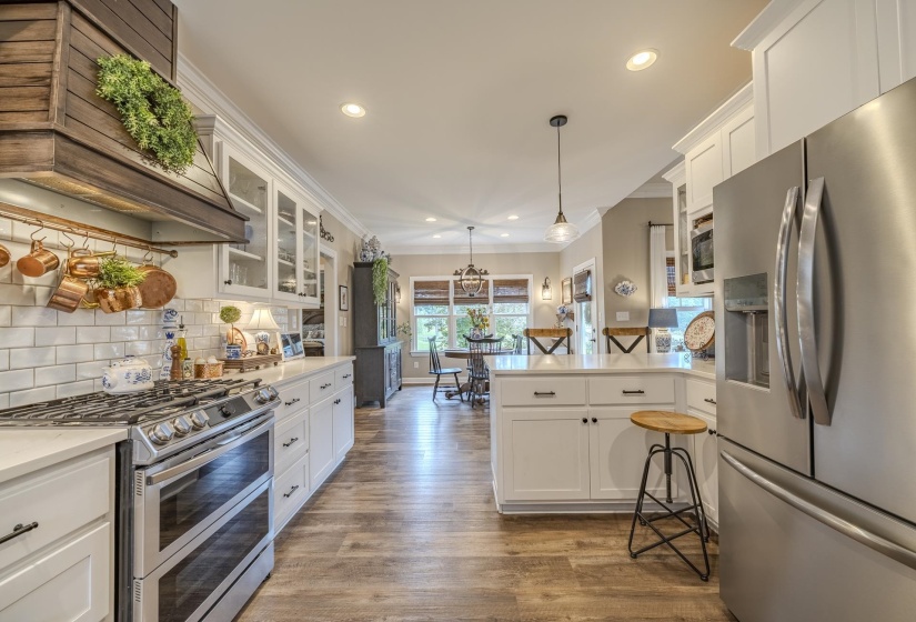 Kitchen featuring stainless steel appliances, wood-finish flooring, white cabinetry, a subway tile backsplash, and recessed lighting