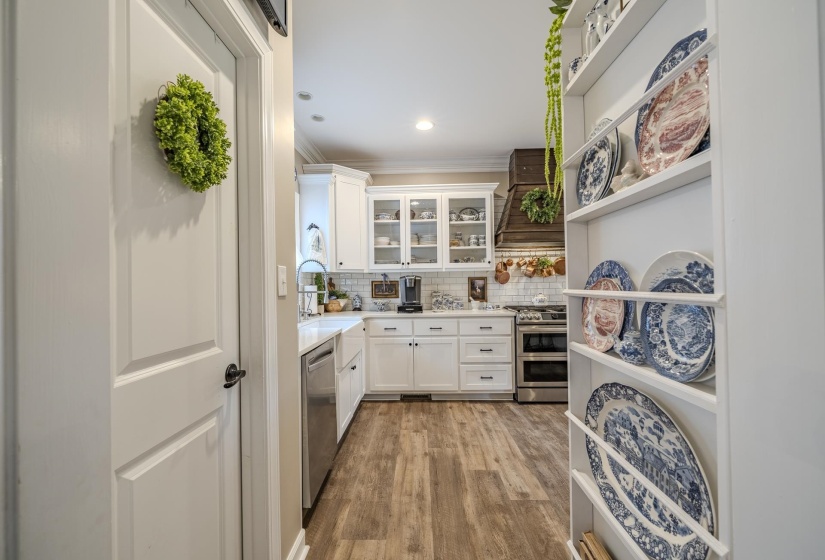 Well-appointed kitchen featuring white cabinetry, wood-finish flooring, a stainless steel dishwasher, a farmhouse sink, and a subway tile backsplash