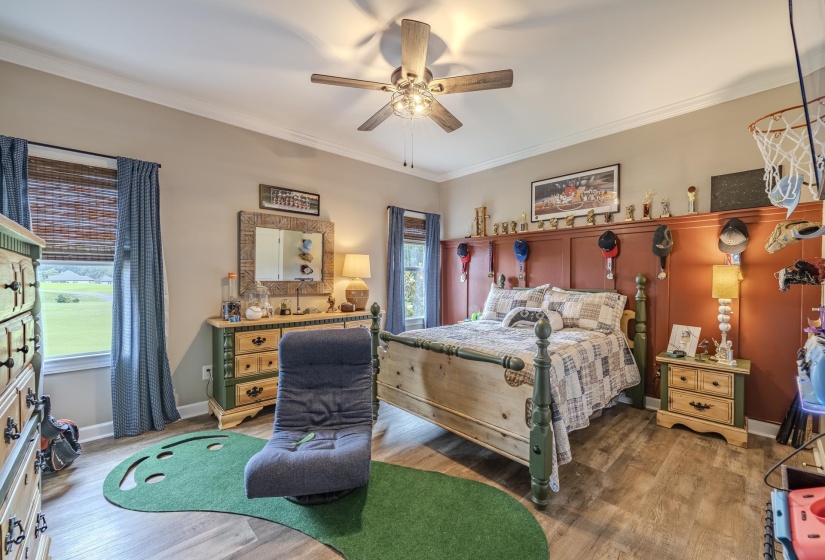 Spacious room featuring wood-finish flooring, a ceiling fan with integrated lighting, and crown molding