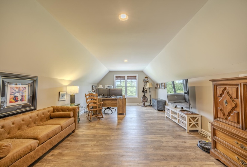 Spacious room featuring wood-finish flooring, recessed lighting, and ample natural light from multiple windows