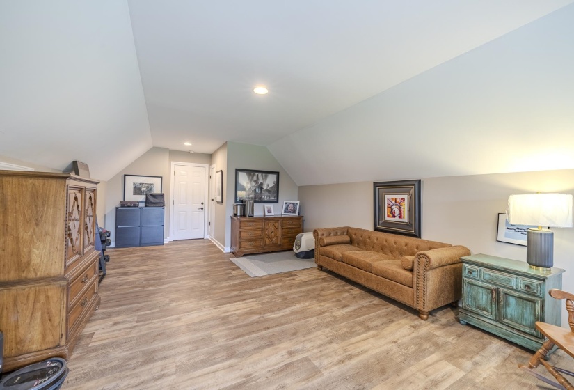 Expansive bonus room featuring wood-finish flooring, sloped ceilings, recessed lighting, and a solid core door