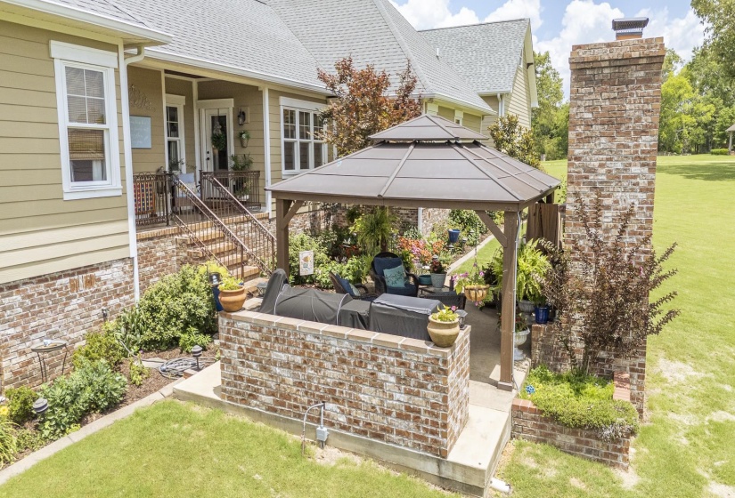 Covered patio with a permanent gazebo, brick knee walls, and landscaping