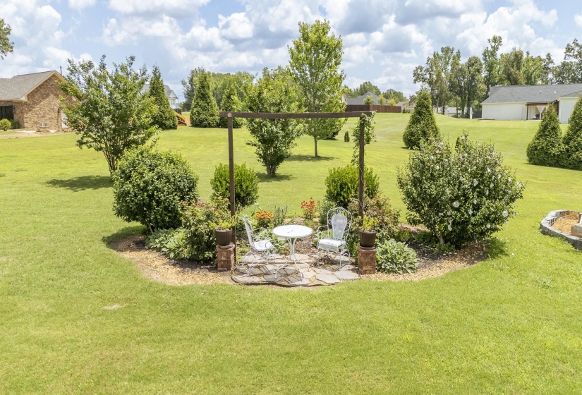 Landscaped garden feature with a stone patio and an overhead arbor