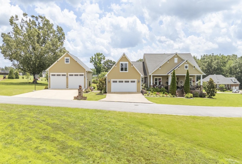 Expansive residential property featuring a main house with a covered front porch, an attached two-car garage, and a detached two-car garage