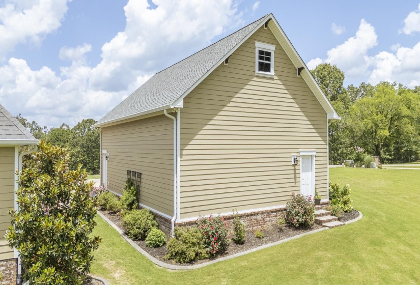 Spacious beige siding structure featuring a gable roof, white-trimmed dormer window, and a white side door