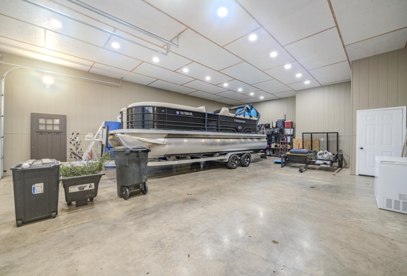 Spacious garage featuring concrete flooring, panel walls, and a finished ceiling with recessed lighting