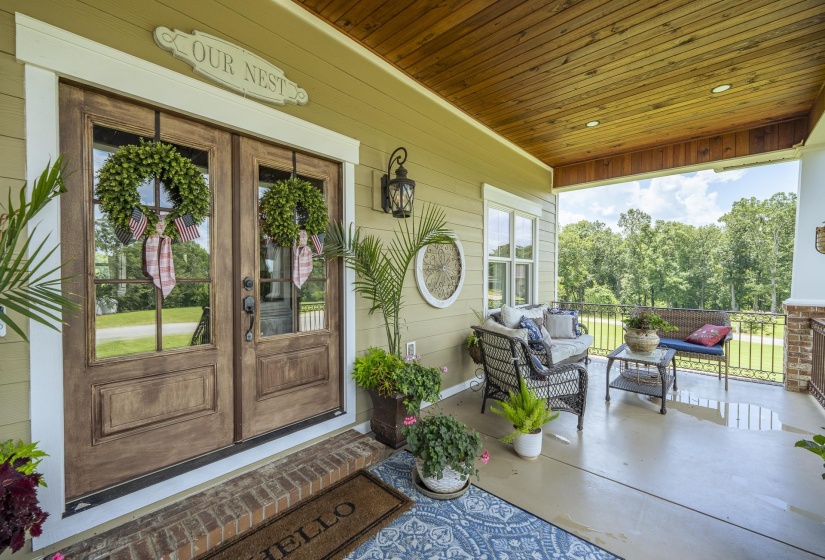 Front porch featuring stained wood double doors with glass lites, a wood-plank ceiling, recessed lighting, a concrete floor, and painted siding