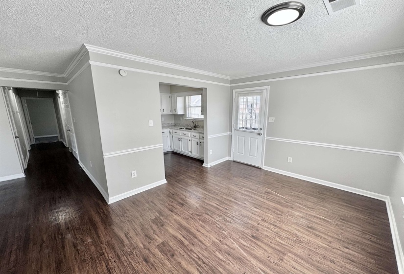 Unfurnished living room with ornamental molding, a textured ceiling, and dark wood-style floors