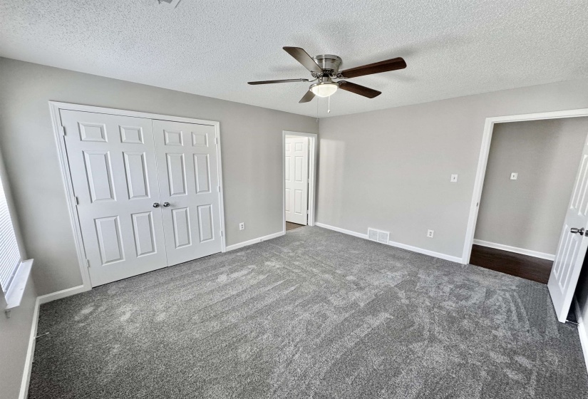 Unfurnished bedroom with a textured ceiling, a closet, dark carpet, and ceiling fan