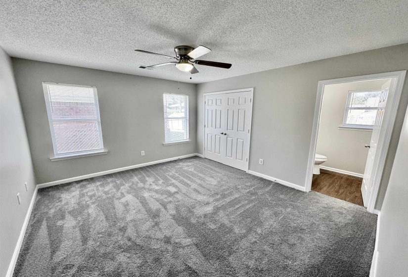 Unfurnished bedroom featuring carpet flooring, a ceiling fan, a textured ceiling, a closet, and connected bathroom