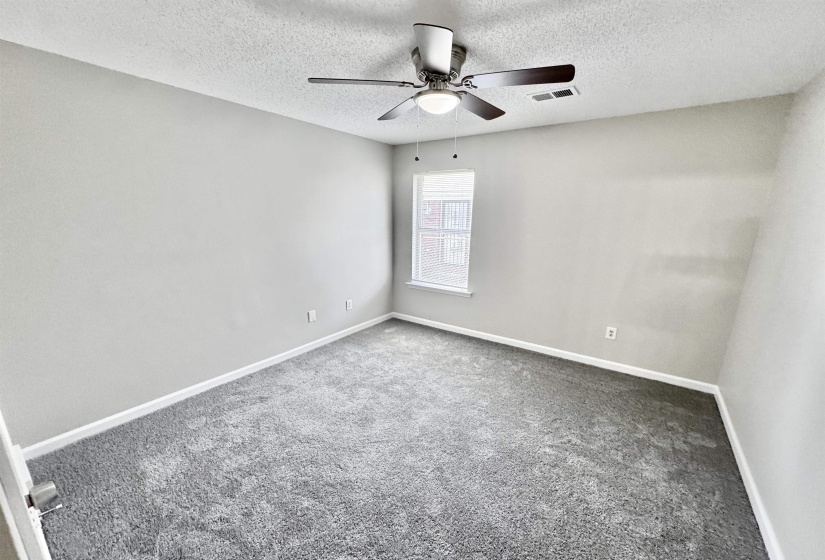 Carpeted spare room featuring a textured ceiling and ceiling fan