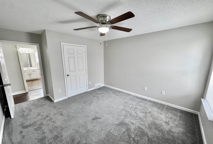 Unfurnished bedroom with a textured ceiling, carpet floors, and a ceiling fan