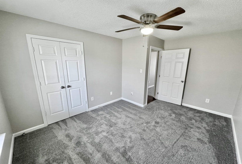 Unfurnished bedroom featuring carpet, a textured ceiling, a closet, and a ceiling fan