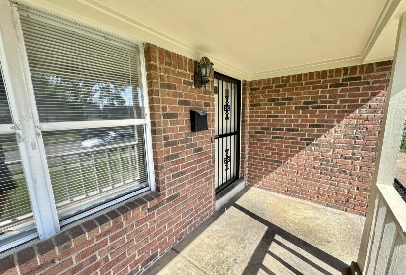Doorway to property featuring brick siding and a porch