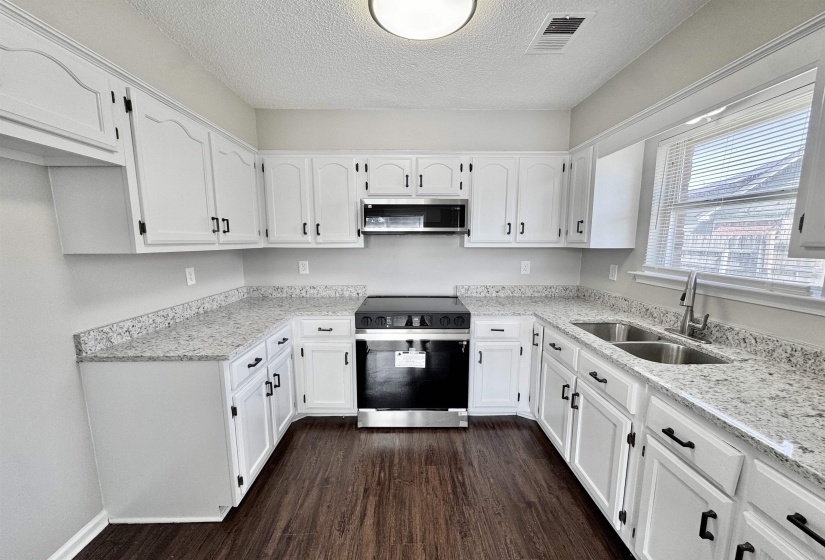 Kitchen featuring black electric range, white cabinetry, dark wood-style floors, and a textured ceiling