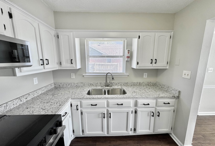 Kitchen with black range with electric stovetop, white cabinetry, dark wood-style floors, and a textured ceiling