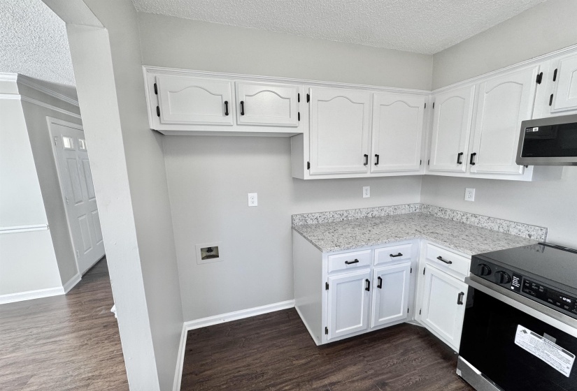 Kitchen featuring a textured ceiling, black electric range, white cabinets, and dark wood finished floors