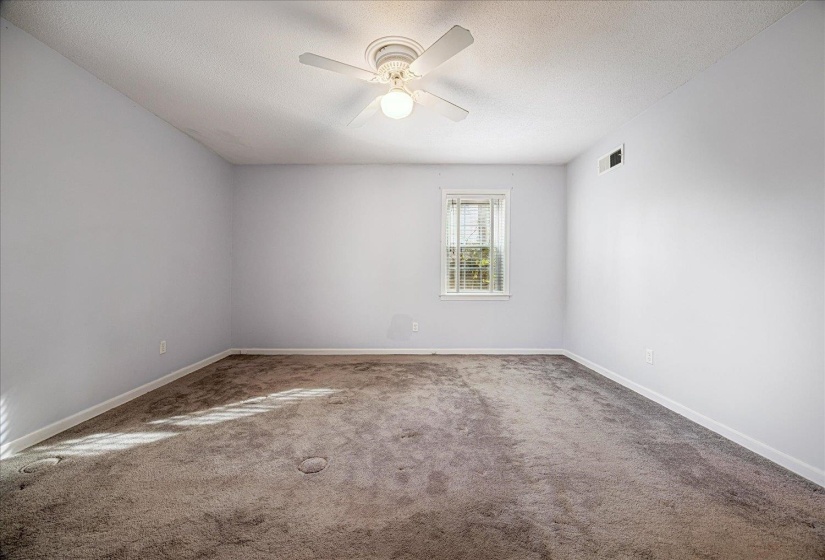 Carpeted empty room featuring a textured ceiling and ceiling fan