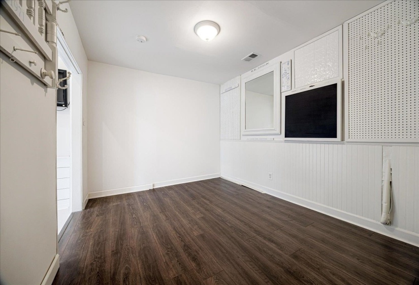 Empty room featuring dark wood-style flooring and a wainscoted wall