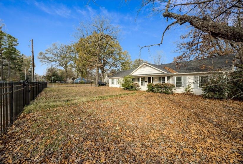 View of yard with a porch, privately gated, iron fenced corner lot