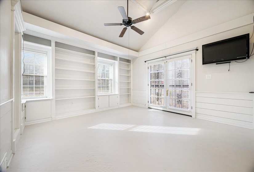 Spare room with a ceiling fan, plenty of natural light, vaulted ceiling, and concrete floors