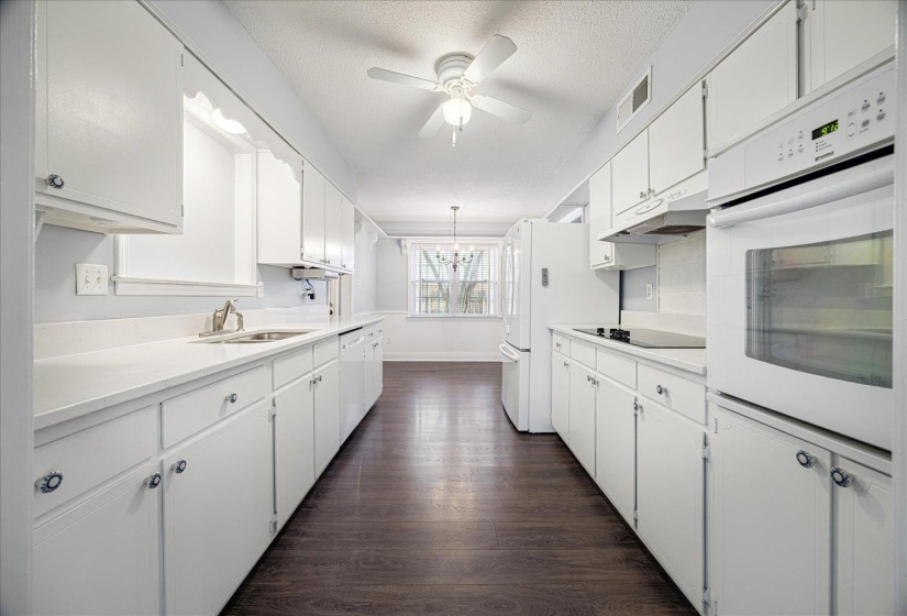 Kitchen with white cabinets, white appliances, dark wood finished floors, a textured ceiling, and a chandelier, granite countertops
