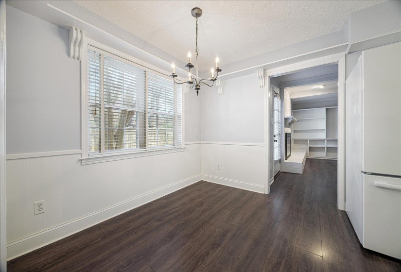 Unfurnished dining area with dark wood finished floors, a chandelier, a textured ceiling, and wainscoting