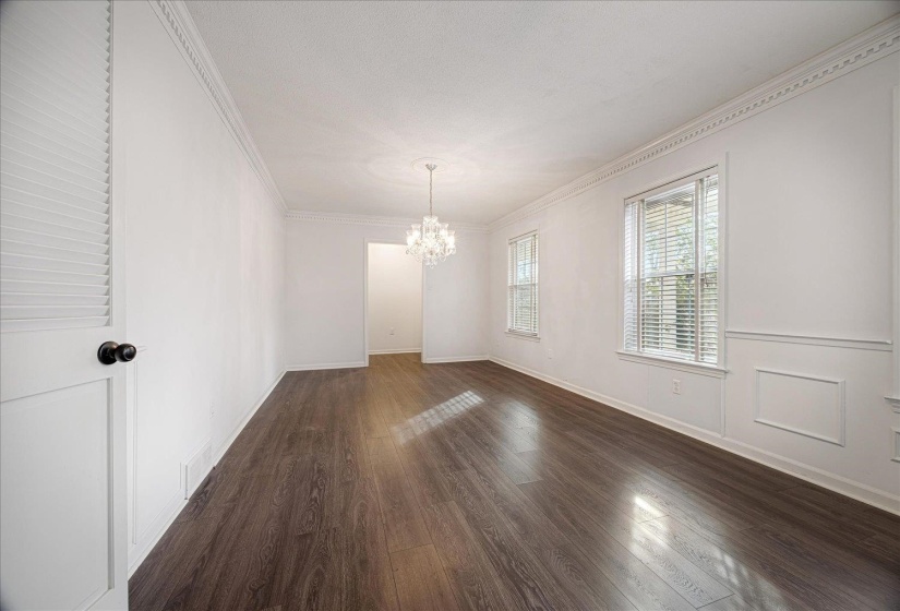 Unfurnished dining area featuring ornamental molding, dark wood-type flooring, and a chandelier