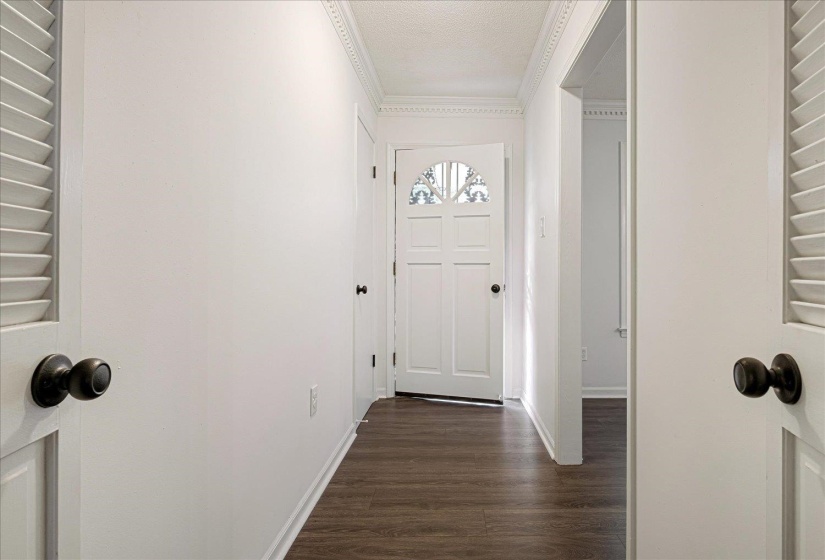 Entryway with wood finished floors and crown molding