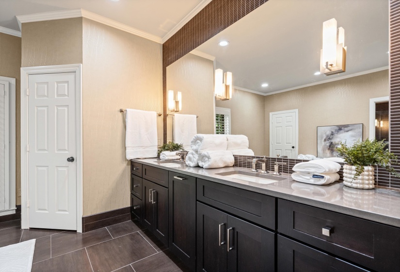 Dual vanity featuring dark wood-finish cabinetry, a light-toned countertop, and undermount sinks with brushed nickel fixtures