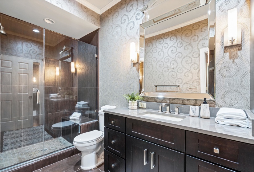 Full bathroom featuring a glass-enclosed shower with tile surround, a white toilet, and a vanity with dark wood-finish cabinetry, a light-colored countertop, and an undermount sink