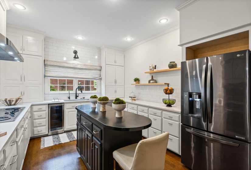 Kitchen featuring white cabinetry, wood-finish flooring, a central island with a dark countertop, white subway tile backsplash, and recessed lighting