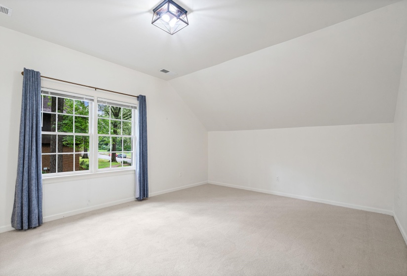 Carpeted room featuring a large multi-pane window, sloped ceilings, and recessed lighting