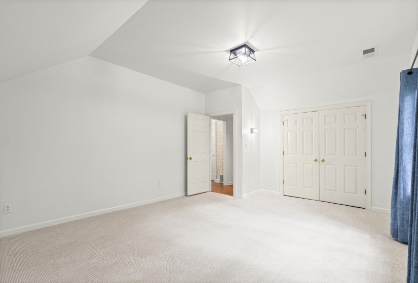 Carpeted room with white walls and a vaulted ceiling