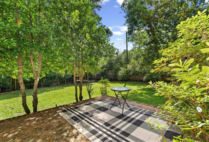 Expansive backyard featuring a manicured lawn, established trees, and surrounding foliage