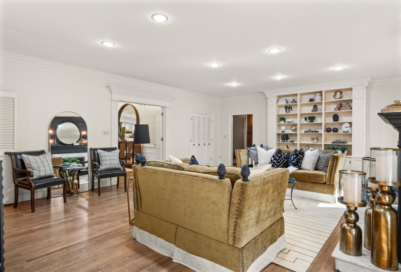 Hardwood flooring throughout featuring recessed lighting, a fireplace with mantel, built-in shelving, and white trim molding
