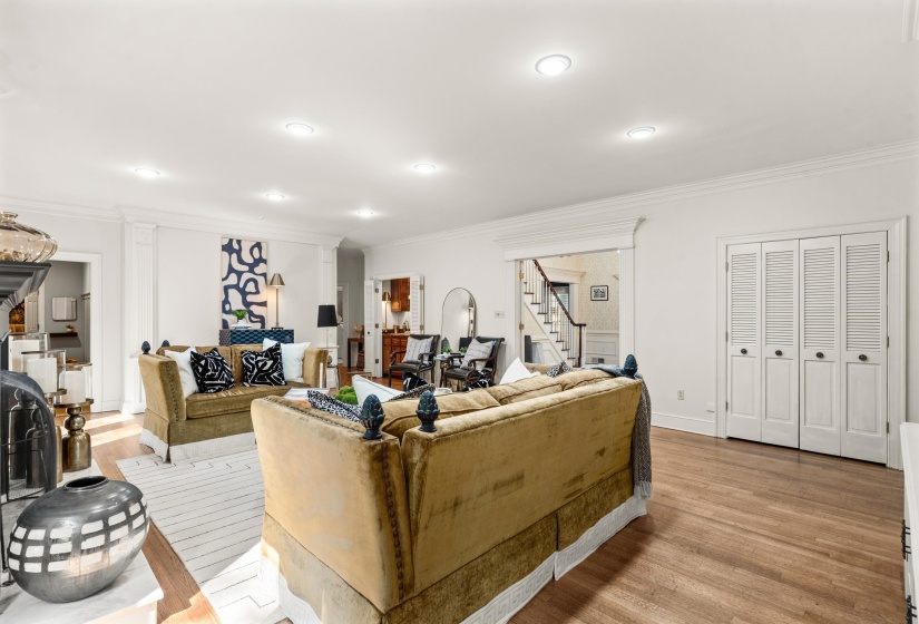 Spacious interior featuring wood-finish flooring, recessed lighting, crown molding, and white bi-fold louvered doors