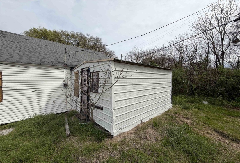 Side exterior featuring white siding and a sloped asphalt shingle roof