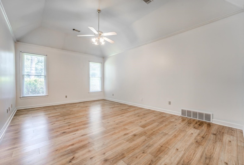 Vaulted ceiling with a ceiling fan, wood-finish flooring, white walls, and two windows