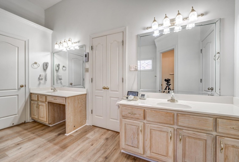 Dual vanities with integrated sinks, wood-finish cabinetry, and overhead lighting fixtures
