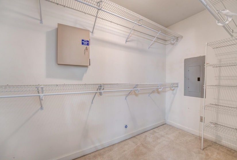 Spacious walk-in closet featuring white wire shelving, hanging rods, and neutral carpeting