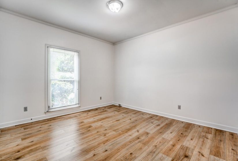 Room featuring wood-finish flooring, white walls, and a single window with blinds
