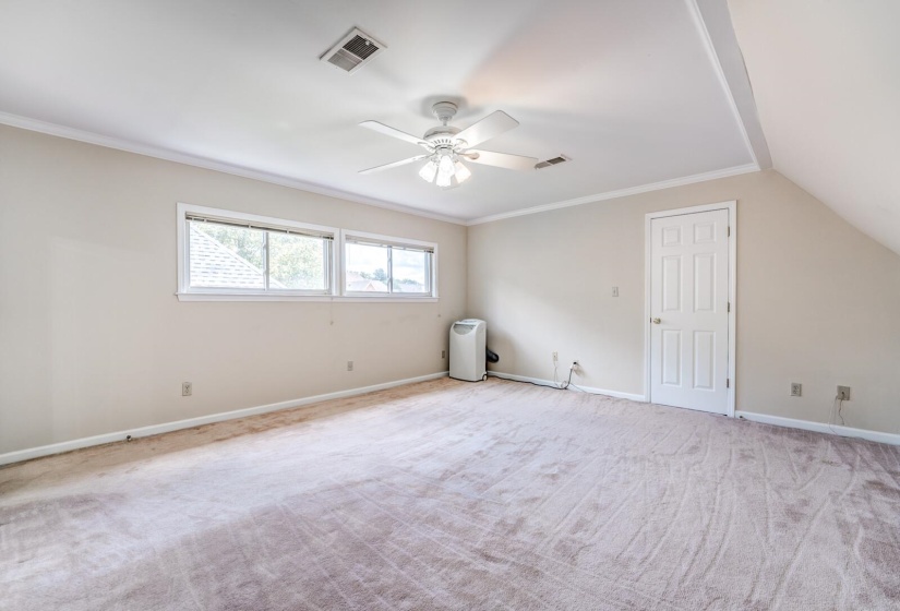 Carpeted room with a sloped ceiling and white trim