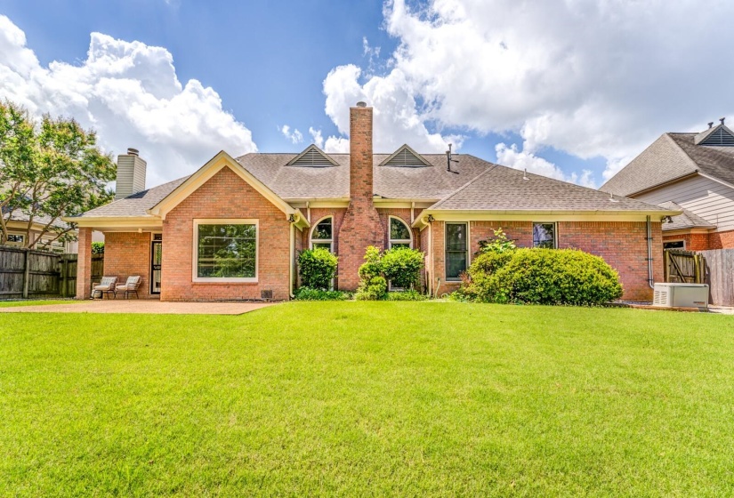 Expansive green lawn with a brick exterior featuring multiple large windows